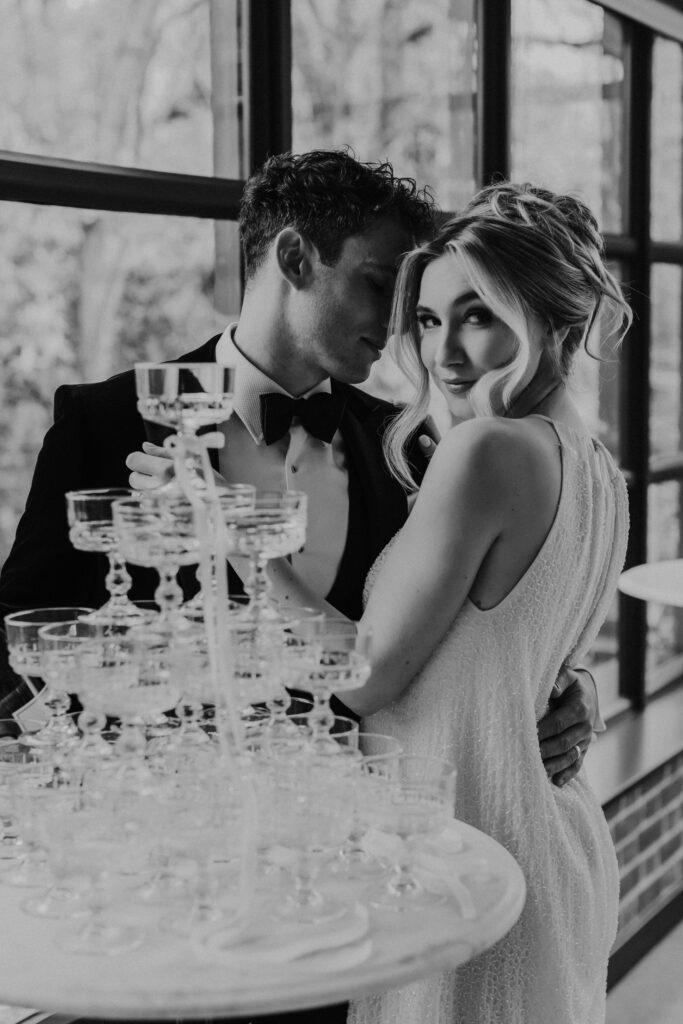 Couple posing by Champagne tower at elegant Essex wedding reception