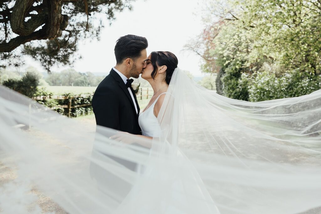 Editorial wedding portrait with bride’s veil blowing in the wind