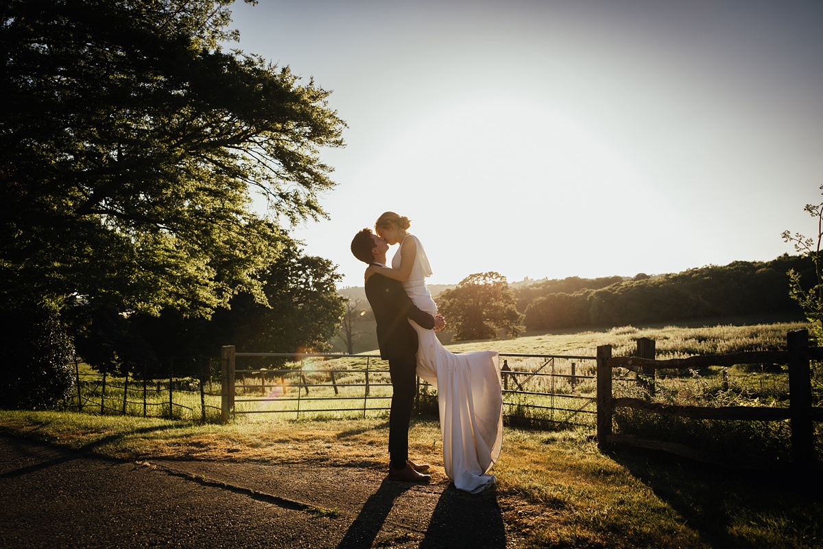 Groom lifting bride during golden hour Essex countryside wedding